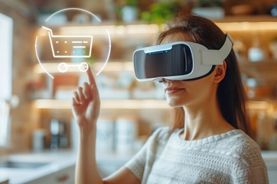 Imagem de uma mulher usando um óculos de realidade virtual em um ambiente doméstico, aparentemente simulando uma experiência de compra virtual. Ela interage com um ícone de carrinho de compras projetado no ar, tocando-o com o dedo. A cena evoca uma sensação de tecnologia avançada e imersiva, representando o uso da realidade virtual para atividades de e-commerce e experiência de compra interativa.