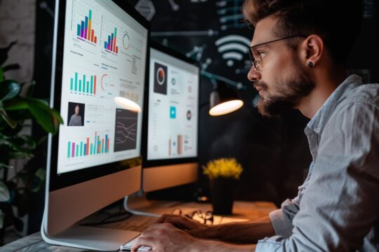 Profissional analisando dados de marketing no computador para decisões estratégicas baseadas em métricas.